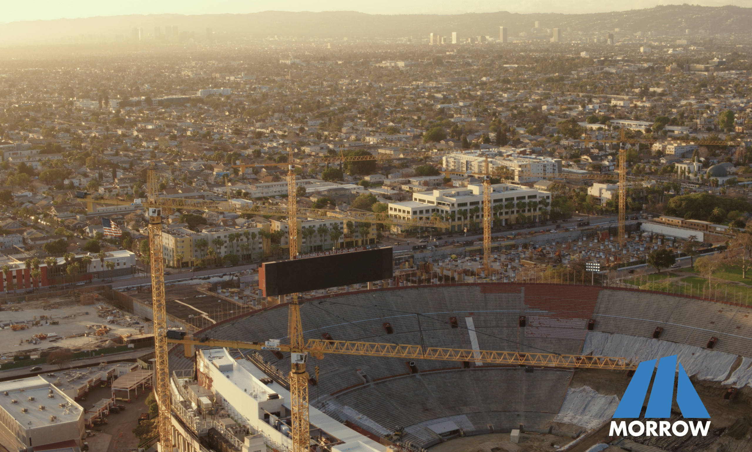 Stadium construction with cityscape background at sunset.