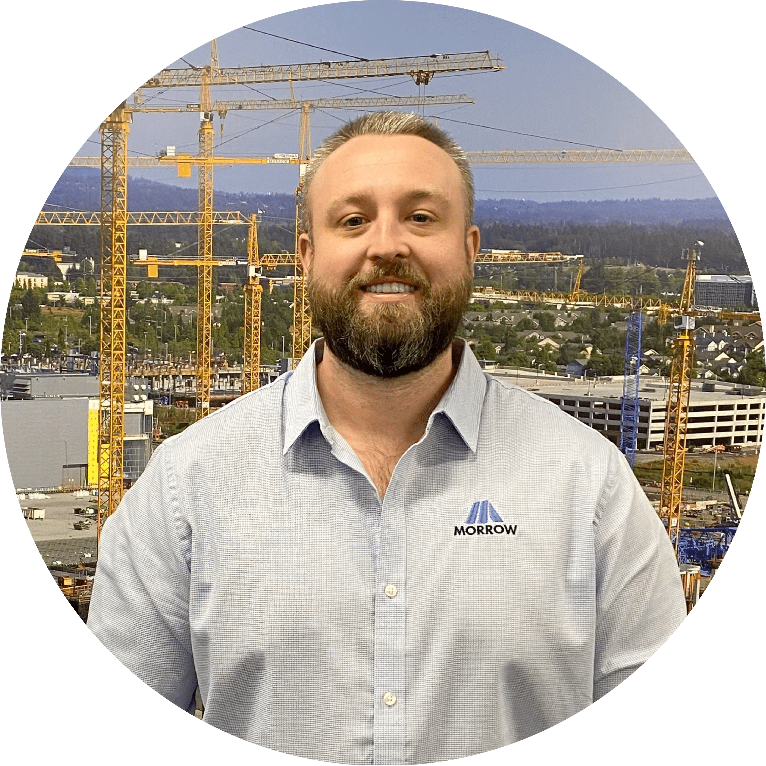 Man in construction setting with cranes in background.